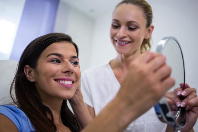 A happy patient looking at her face in the mirror