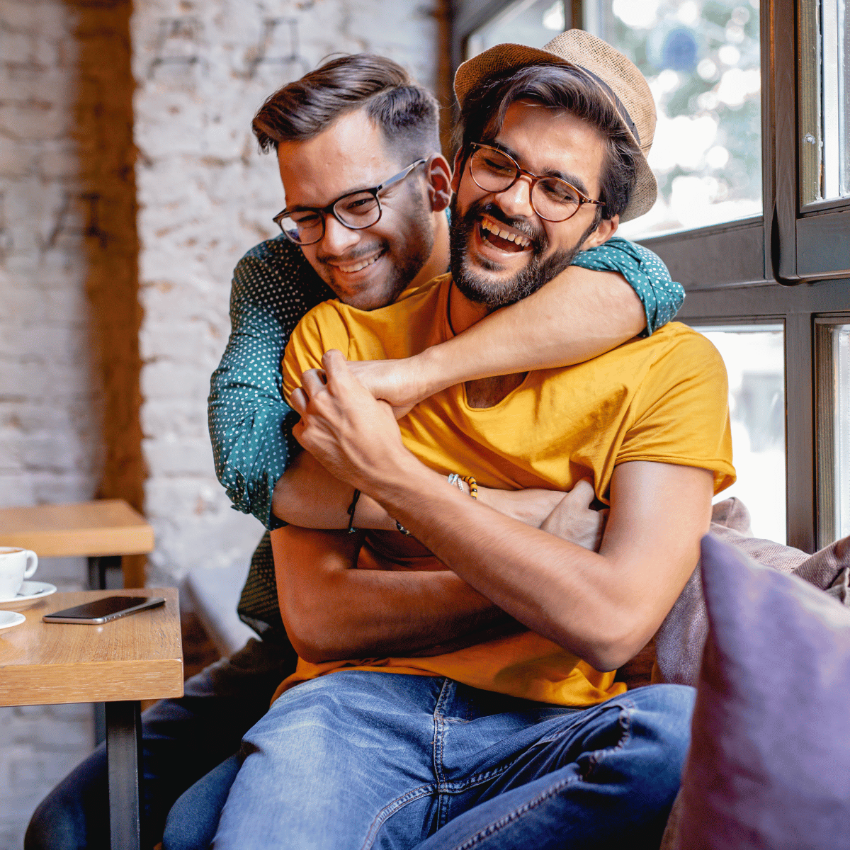 A gay couple hugging each other and laughing.