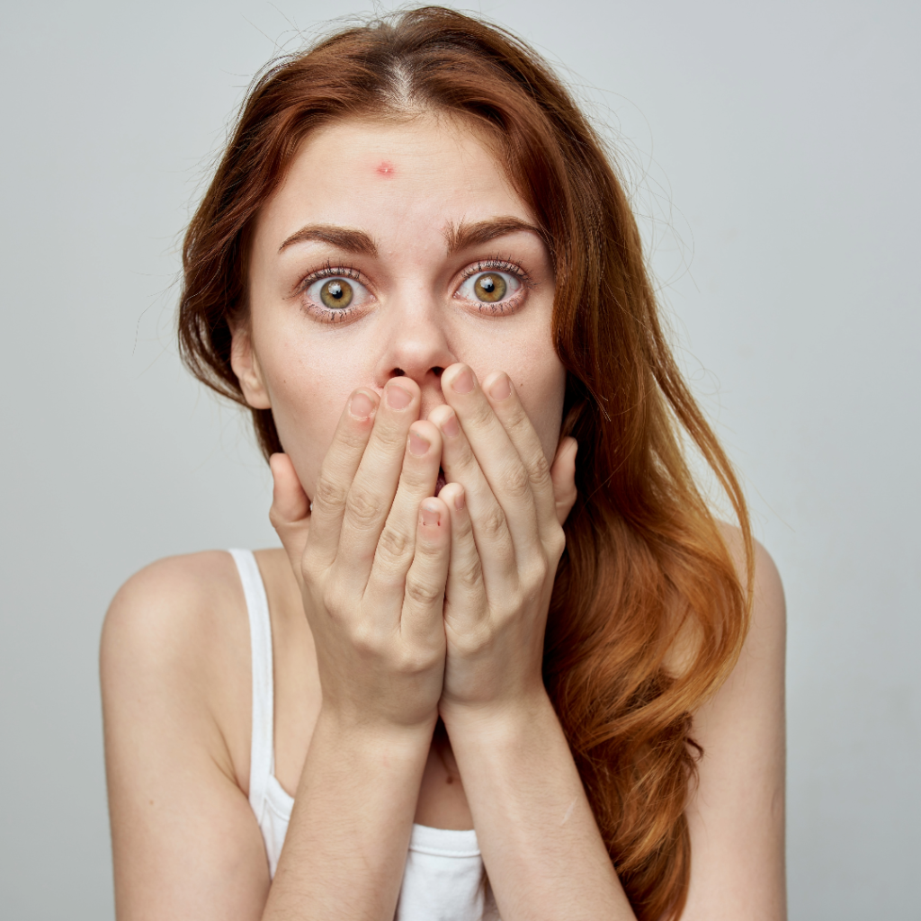 surprised woman looking in the mirror and seeing acne