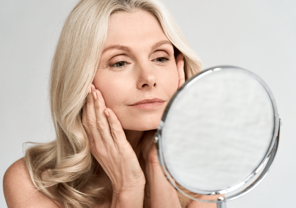 A woman touching her skin as she looks in the mirror